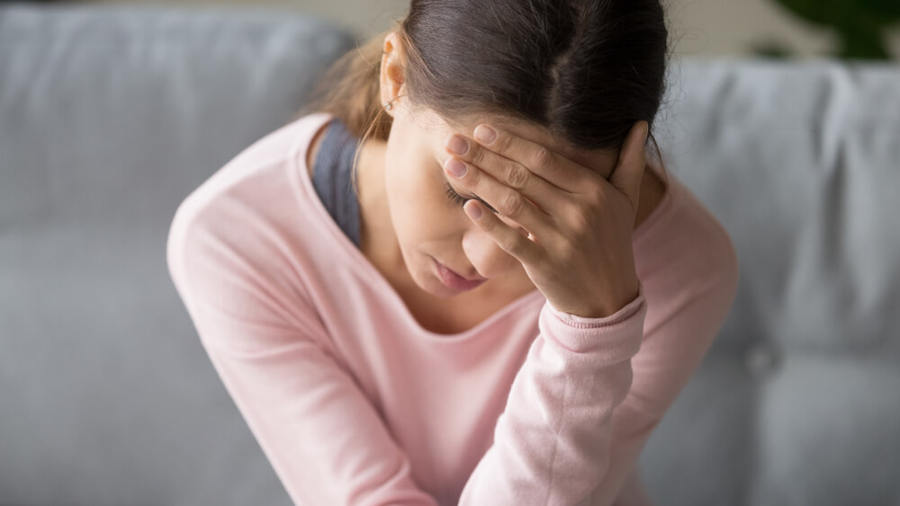 Young woman holding her head suffering from migraine