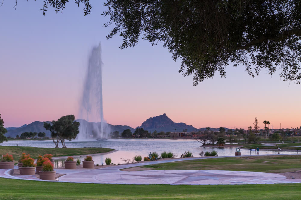 Pink sky behind one of the tallest fountains in the world in Fountain Hills, AZ with Fire Rock and Four Peaks in the background