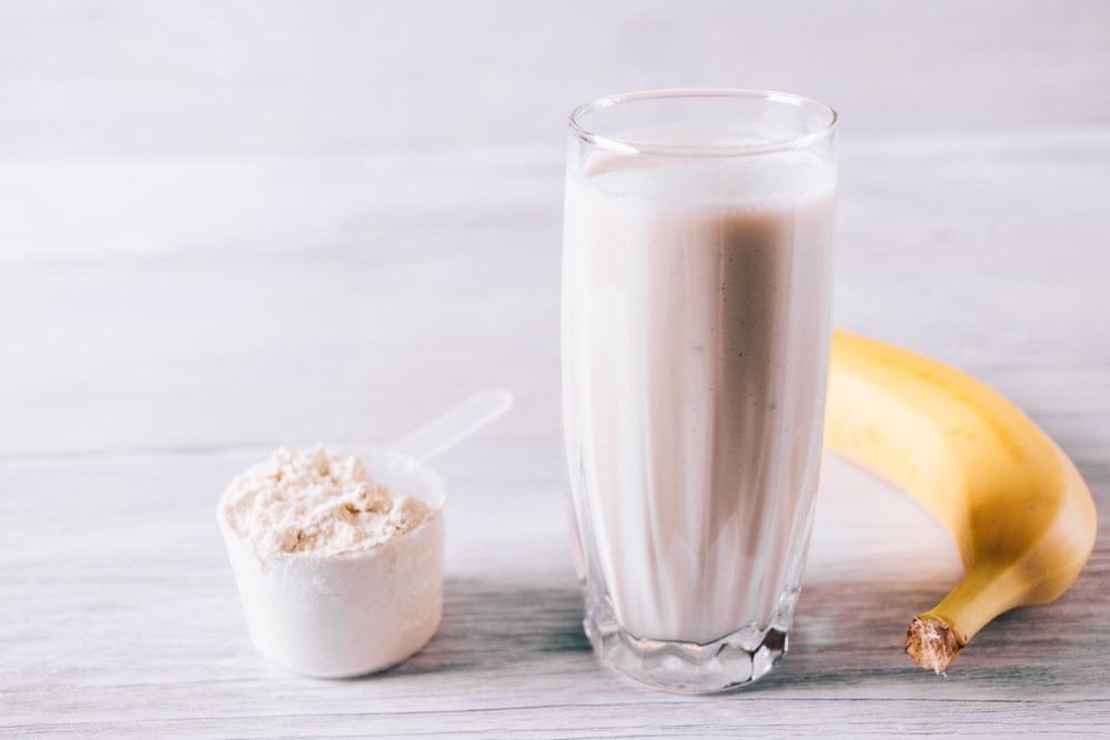 Close up of a protein shake, a scoop of protein powder and a banana