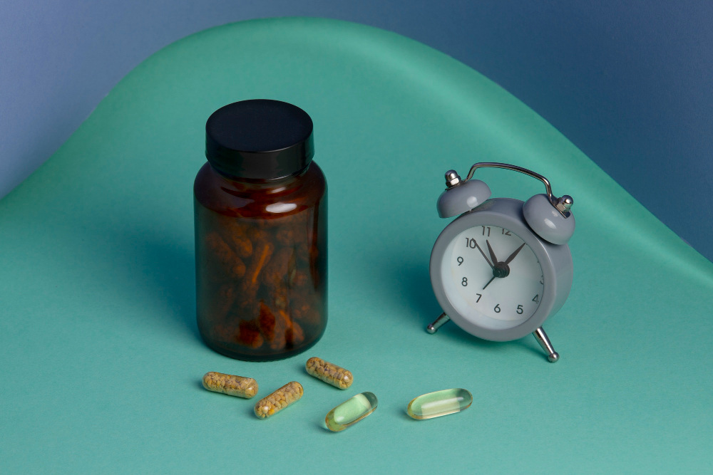 Supplement bottle and capsules beside an alarm clock